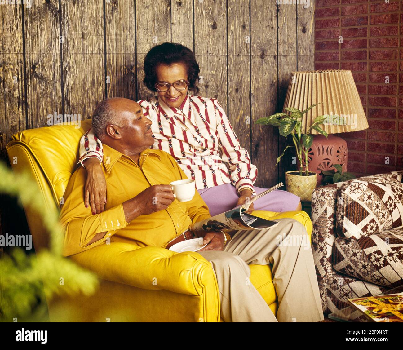 1970s 1980s MATURE AFRICAN-AMERICAN COUPLE SITTING ON YELLOW LEATHER CHAIR DRINKING COFFEE HOLDING MAGAZINE WOOD PANELED ROOM - kf12714 PHT001 HARS YELLOW COLOR SENIORS OLD TIME NOSTALGIA OLD FASHION RETIRED 1 STYLE COMMUNICATION INFORMATION STRONG JOY LIFESTYLE SATISFACTION ELDER FEMALES STRIPED MARRIED SPOUSE HUSBANDS HOME LIFE COPY SPACE FRIENDSHIP HALF-LENGTH LADIES PERSONS CARING MALES STRIPES RETIREMENT SENIOR MAN SENIOR ADULT PARTNER SENIOR WOMAN RETIREE HAPPINESS OLDSTERS HIGH ANGLE OLDSTER LEISURE LIVING ROOM AFRICAN-AMERICANS AFRICAN-AMERICAN BLACK ETHNICITY BLOUSE PANELED ELDERS Stock Photo