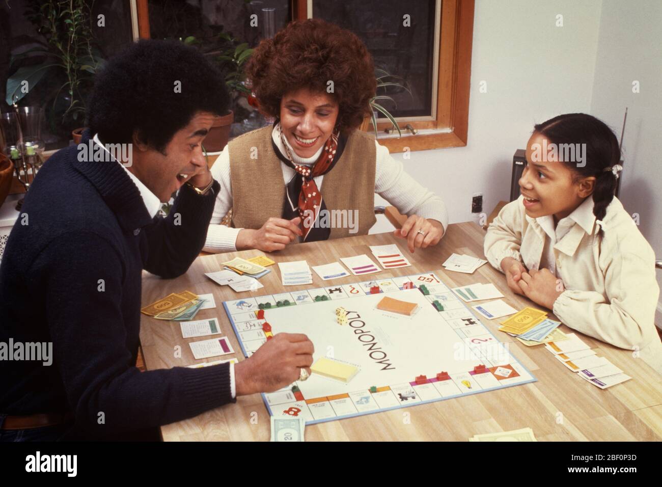 1970s 1980s ANIMATED SMILING COMPETING AFRICAN-AMERICAN FAMILY MOTHER FATHER DAUGHTER PLAYING MONOPOLY BOARD GAME TOGETHER - kj8848 PHT001 HARS 3 DAD MOM CLOTHING INDOORS FACES NOSTALGIC PAIR SUBURBAN URBAN COLOR MOTHERS EXPRESSION OLD TIME NOSTALGIA OLD FASHION 1 SILLY JUVENILE FACIAL STYLE COMMUNICATION COMIC COMPETITION STRONG PLEASED FAMILIES JOY LIFESTYLE FEMALES MARRIED SPOUSE HUSBANDS HOME LIFE COPY SPACE FRIENDSHIP HALF-LENGTH LADIES DAUGHTERS PERSONS AFRO CARING MALES RISK ENTERTAINMENT EXPRESSIONS FATHERS PARTNER GOALS HUMOROUS HAPPINESS CHEERFUL HIGH ANGLE LEISURE AFRICAN-AMERICANS Stock Photo