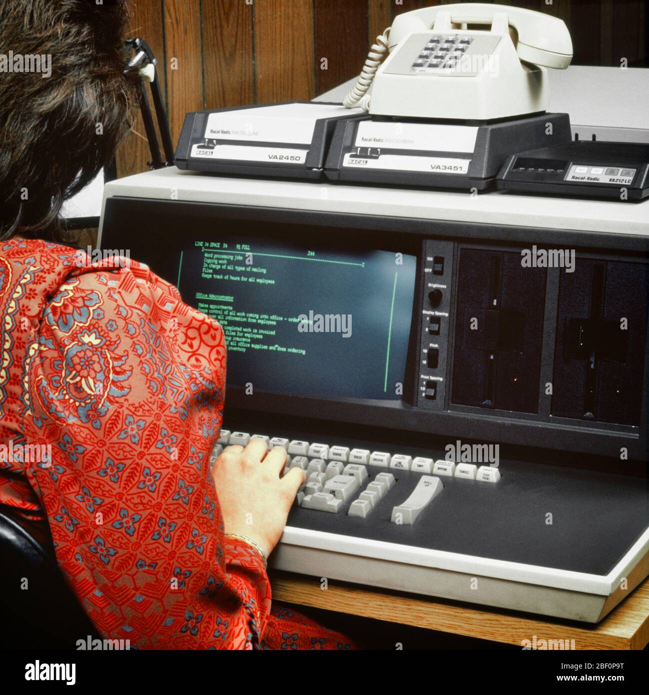 1980s BACK OF ANONYMOUS WOMAN WEARING RED PAISLEY DRESS WORKING ON EARLY COMPUTER TERMINAL KEYBOARD WITH DIAL-UP TELEPHONE MODEM - ko1556 PHT001 HARS FEMALES JOBS UNITED STATES COPY SPACE LADIES PERSONS UNITED STATES OF AMERICA NORTH AMERICA NORTH AMERICAN SKILL OCCUPATION SKILLS HEAD AND SHOULDERS EARLY PAISLEY REAR VIEW OF ON OPPORTUNITY EMPLOYMENT OCCUPATIONS HIGH TECH DATA ENTRY HARDWARE MONITOR ANONYMOUS EMPLOYEE BACK VIEW DIAL-UP HIGH-TECH MODEM PROGRAMMER TERMINAL YOUNG ADULT WOMAN CAUCASIAN ETHNICITY OLD FASHIONED Stock Photo