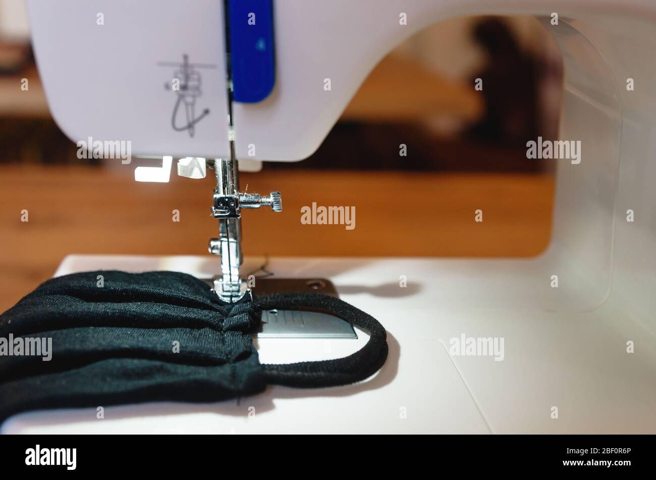 Sewing a black home made face nose mask old t-shirt and hair ribbon as  protection against corona virus covid-19 on a machine Stock Photo - Alamy