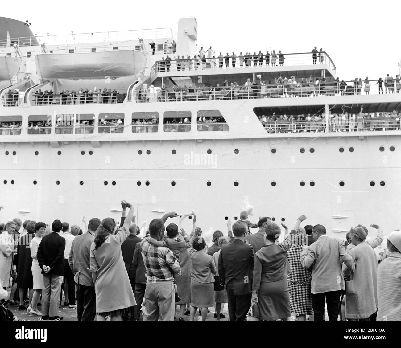 1960s 1970s CRUISE SHIP LEAVING PORT PASSENGERS WAVING BON VOYAGE TO FRIENDS AND FAMILY LEFT ON THE DOCK - s16712 HAR001 HARS PORT HAPPINESS BON ADVENTURE LEISURE TRIP AND GETAWAY EXCITEMENT LOW ANGLE VOYAGE HOLIDAYS JOURNEY UPSCALE BON VOYAGE AFFLUENT ESCAPE LEFT VACATIONS WELL-TO-DO BLACK AND WHITE HAR001 OLD FASHIONED VESSEL Stock Photo