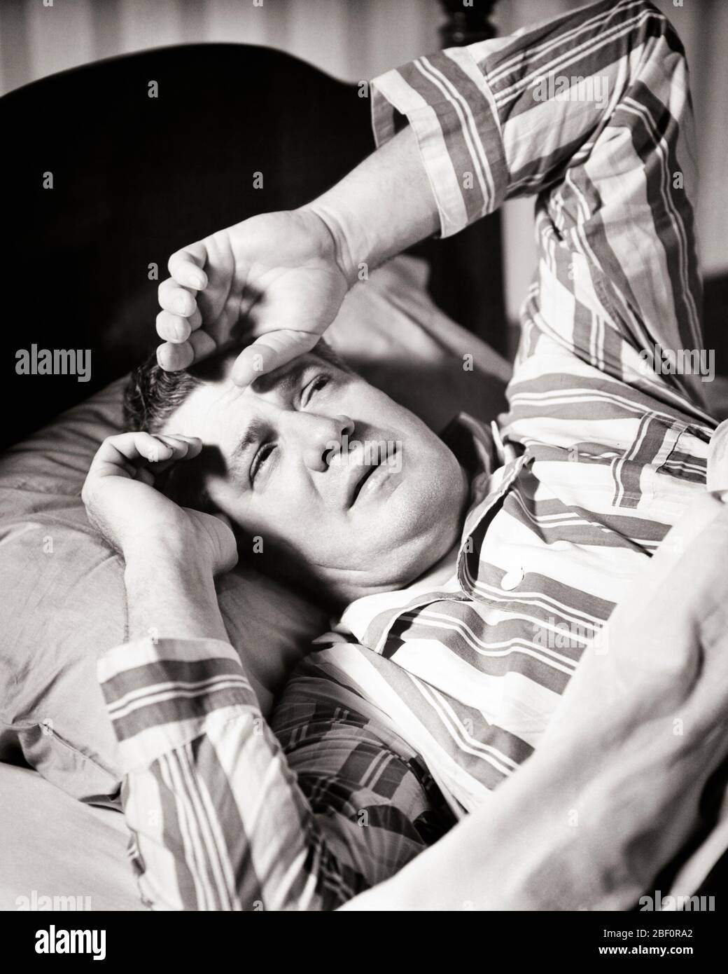 1940s MATURE MAN IN BED WEARING STRIPED PAJAMAS HAND TO FOREHEAD PAINED ...