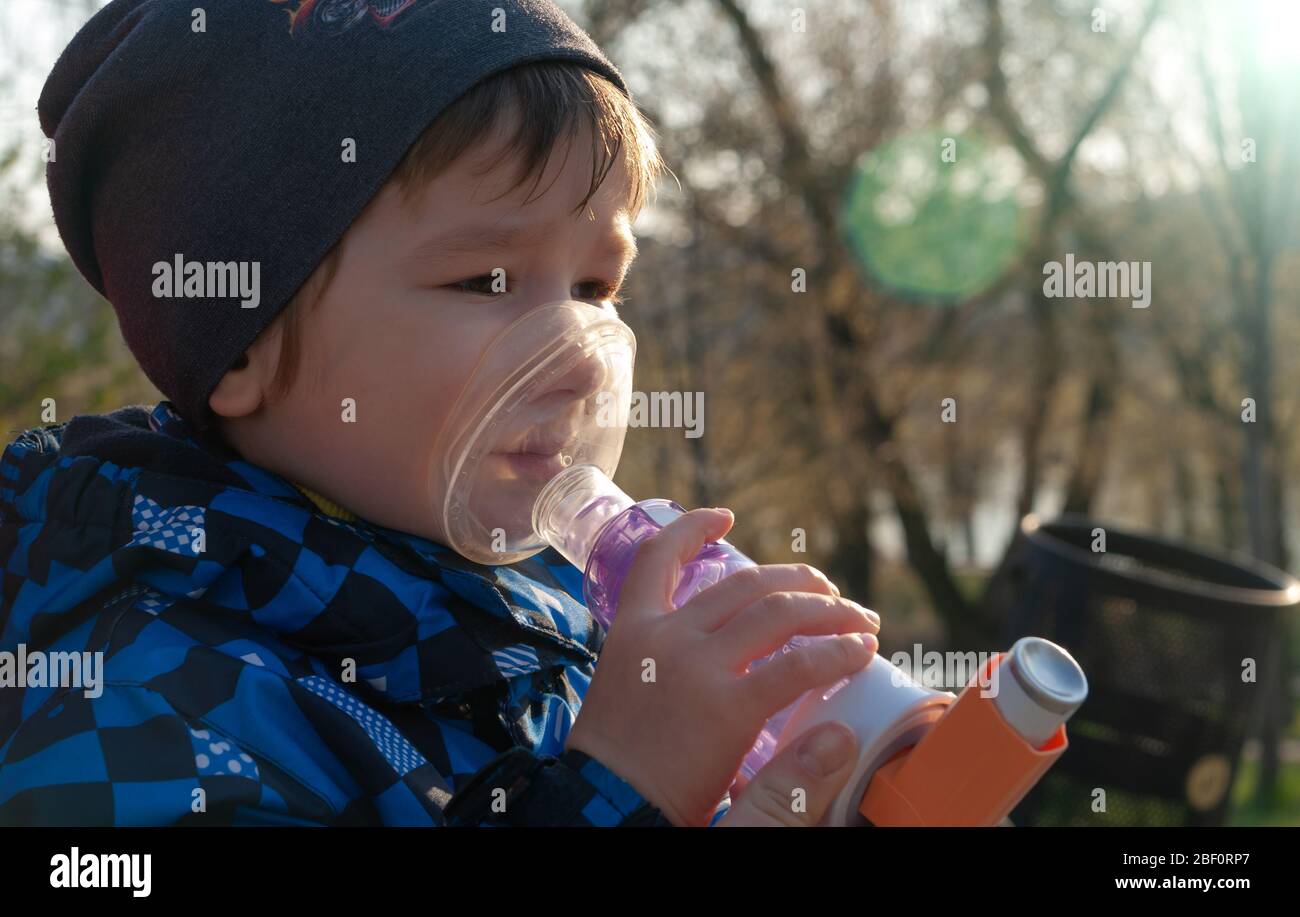 A small boy who suffering from illness bronchial asthma getting treatment with aerosol inhaler. Prevention of complications Stock Photo
