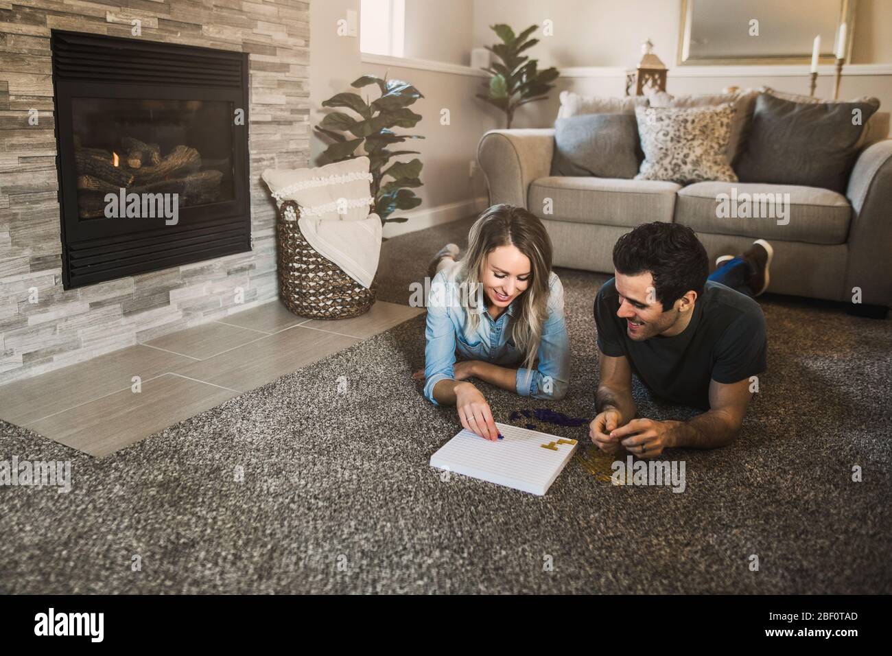 young couple playing a board game in their cozy living room Stock Photo