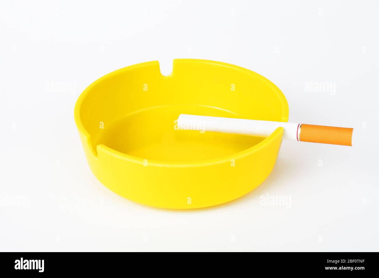 Yellow ashtray with cigarette on a white background, isolate Stock