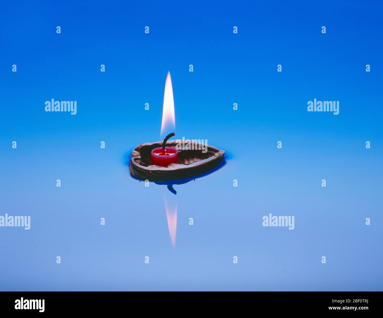 Burning candle in nutshell floats on water hires stock photography and