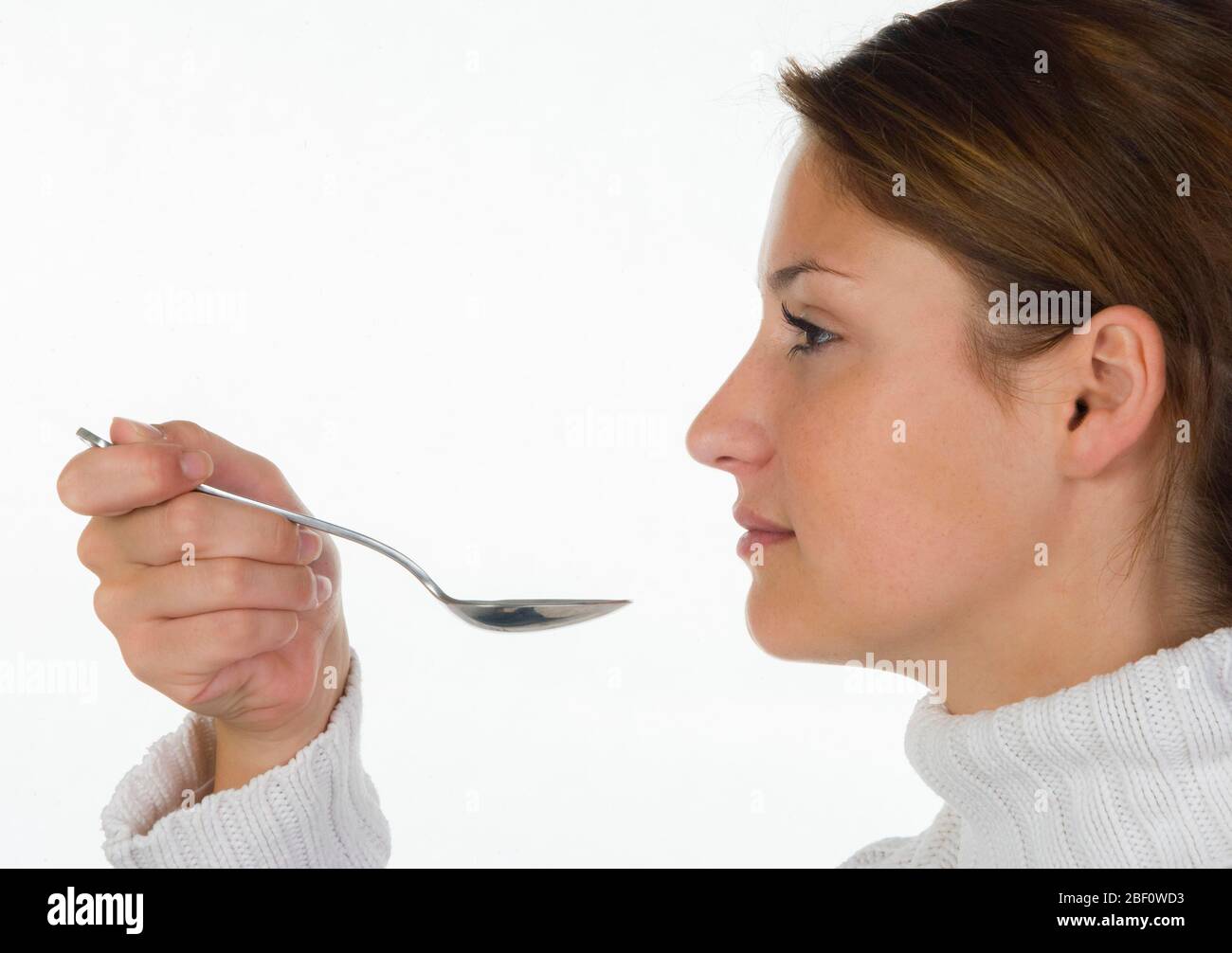 Young woman, with cold, takes medicine on spoon, 20 years, Austria