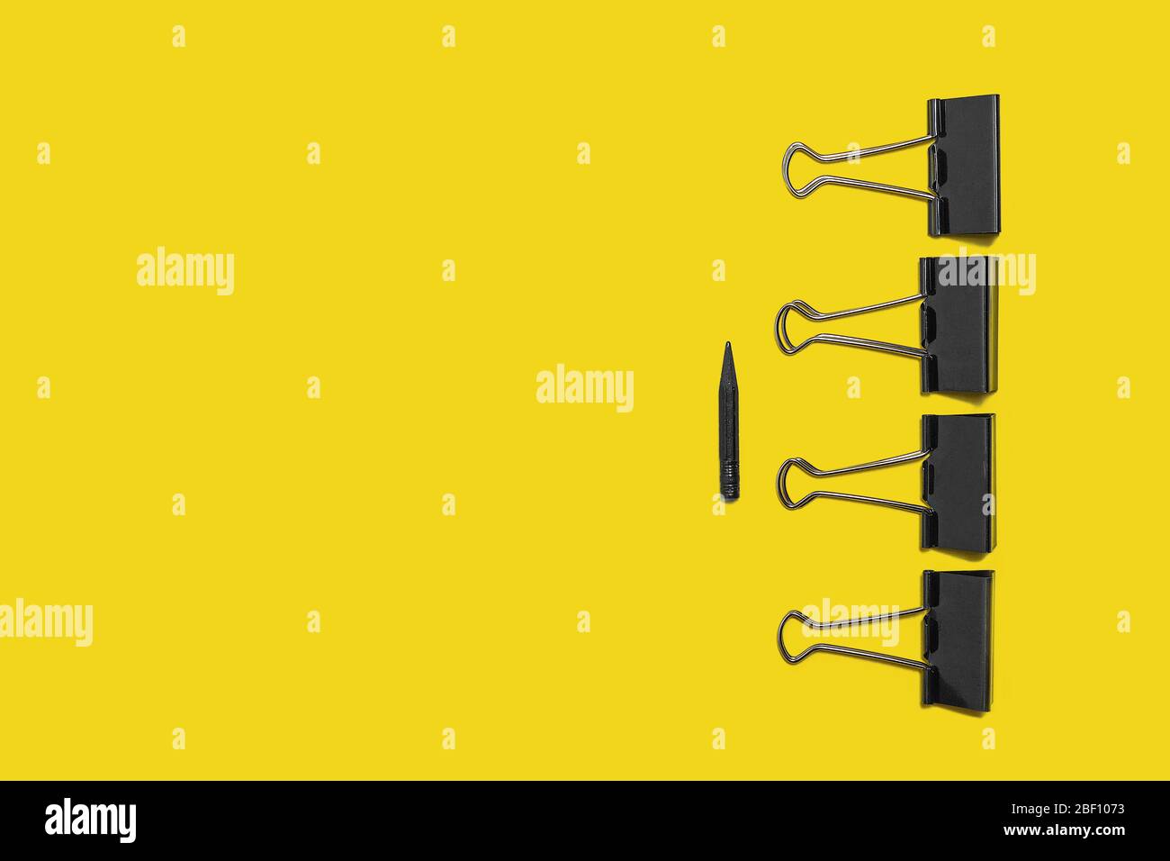 four big paper clips against small pencil Stock Photo