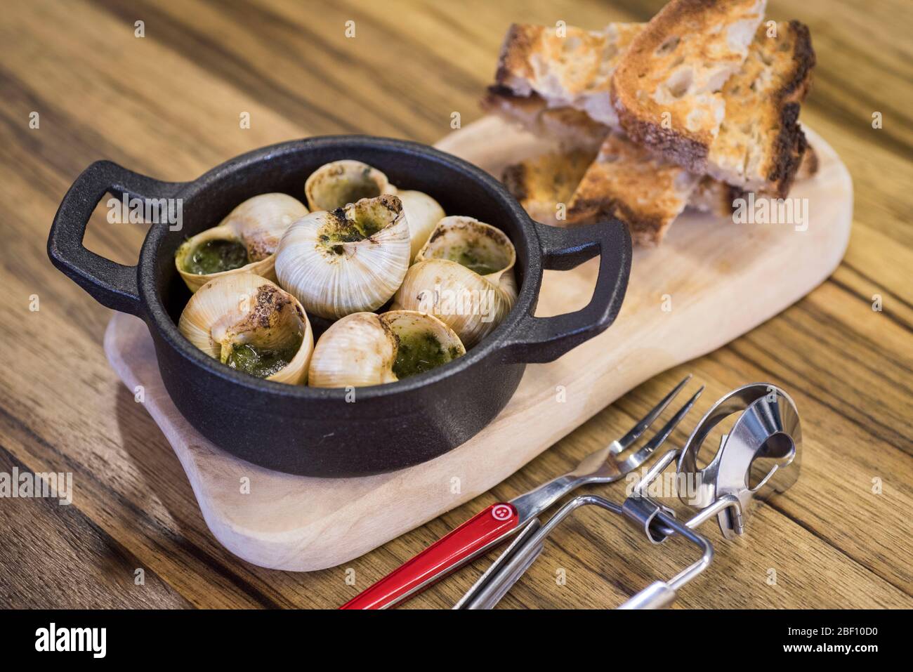 A dish of snails in garlic sauce served with toast Stock Photo