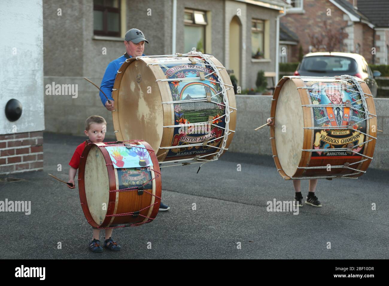 Mark Black and his sons, Thomas (left), four, and Adam, 10, from Markethill in County Armagh, Northern Ireland, play Lambeg drums outside their home to salute local heroes during Thursday's nationwide Clap for Carers initiative to recognise and support NHS workers and carers fighting the coronavirus pandemic. Stock Photo