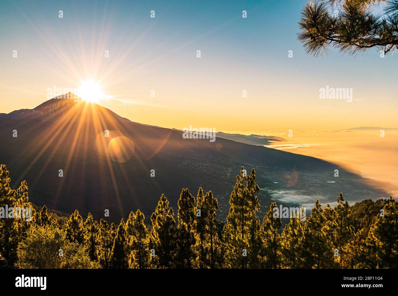 Sun flare as the sun sets behind Mount Teide, seen from Mirador de Chipeque viewpoint. Tenerife, canary Islands, Spain. Stock Photo