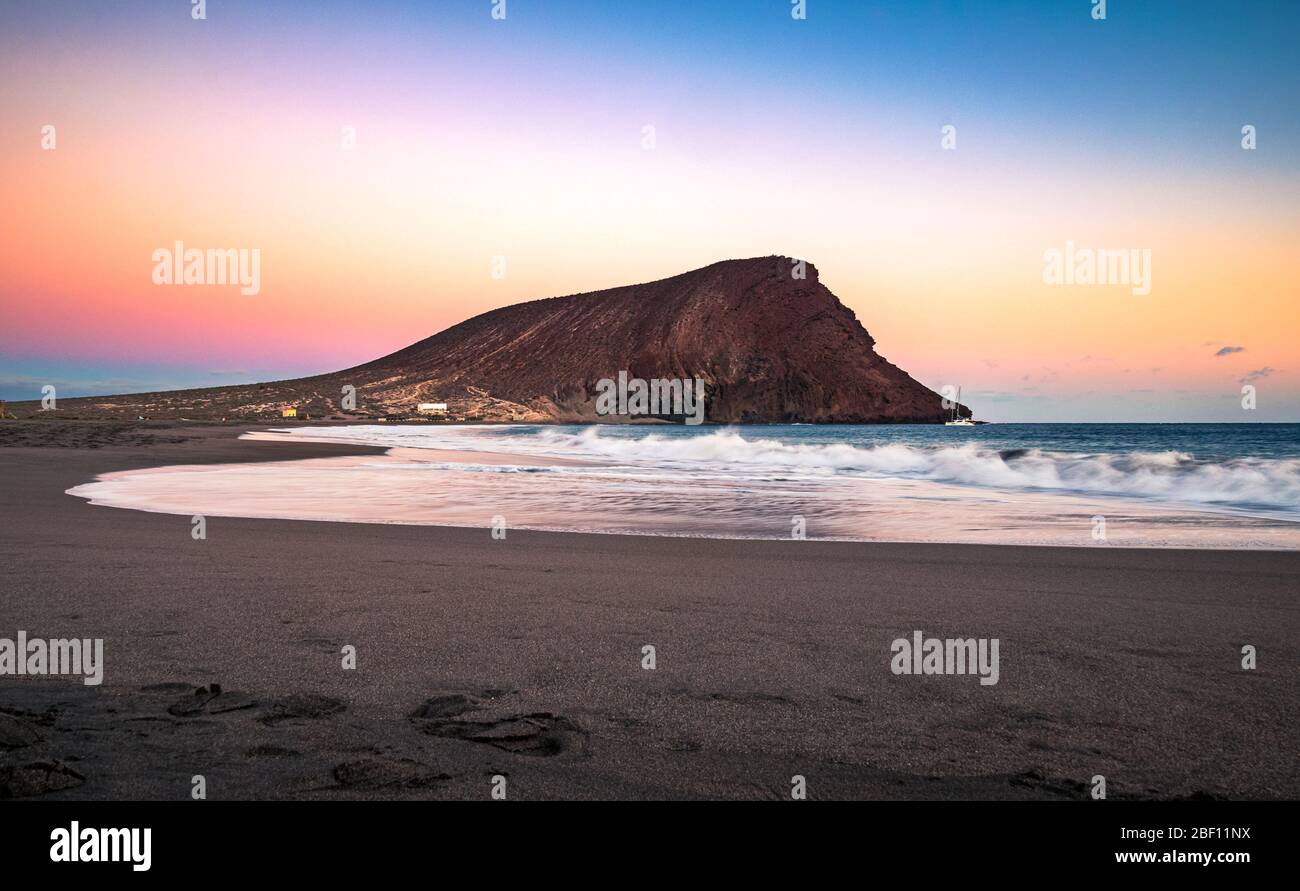Colorful sky after sunset at La Tejita beach with the iconic 'Red Hill' (La Montaña Roja) in the South of Tenerife, Canary Islands, Spain. Stock Photo