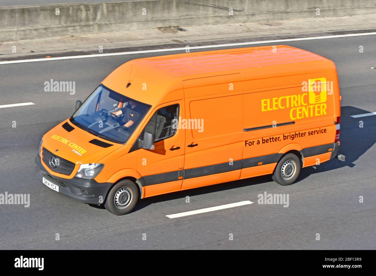 Orange Mercedes delivery van operated by Electric Centre an electrical wholesaler business completes supply chain to customers driving on UK motorway Stock Photo