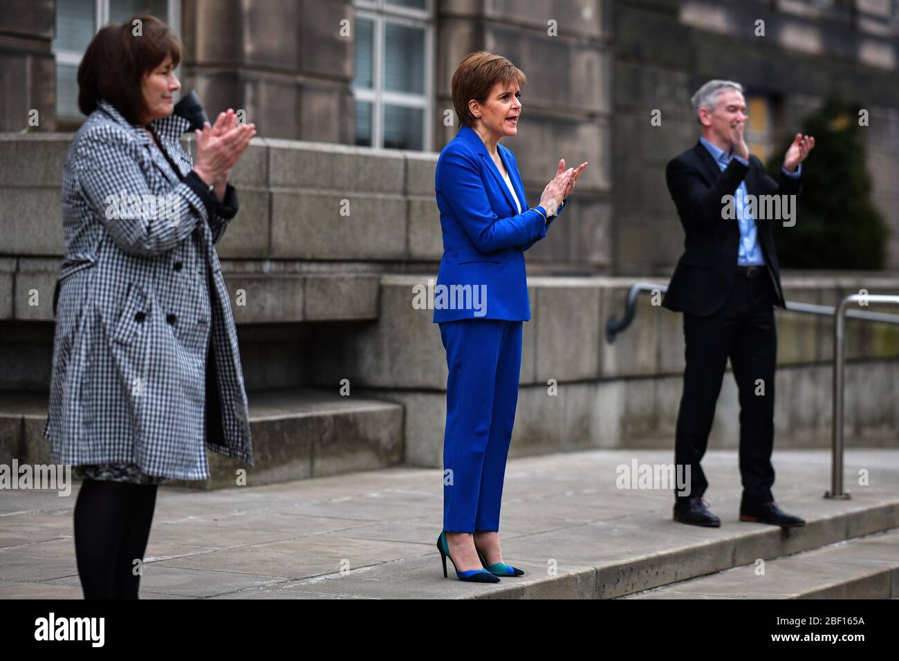 (left to right) Health Secretary Jeane Freeman, First Minister Nicola Sturgeon and Dr Gregor Smith Scotland's interim chief medical officer applaud outside St Andrew's House, the headquarters building of the Scottish Government in Edinburgh, to salute local heroes during Thursday's nationwide Clap for Carers initiative to recognise and support NHS workers and carers fighting the coronavirus pandemic. Stock Photo