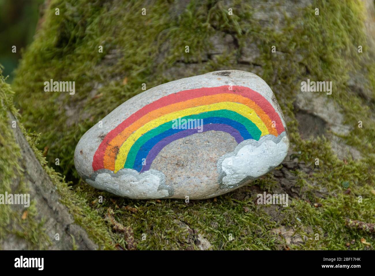 The kindness rocks project, a pebble painted with a rainbow in the woods during the coronavirus covid-19 pandemic, UK Stock Photo