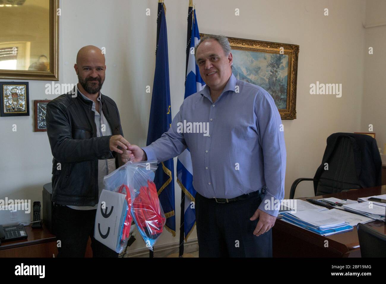 (200416) -- PIRAEUS (GREECE), April 16, 2020 (Xinhua) -- Elias Salpeas (L), advisor of the municipality of Piraeus on new technologies and head of the Blue Lab, delivers 3D printed face shields to a representative of a hospital in Piraeus, Greece, on April 15, 2020. In a hi-tech hub at the Greek port city of Piraeus, experts in new technologies are racing against time day in and day out this April to meet Greek hospitals' needs for personal protective equipment (PPE) in the war against the novel coronavirus pandemic.TO GO WITH 'Feature: In Piraeus, tech experts 3D print face shields for medica Stock Photo