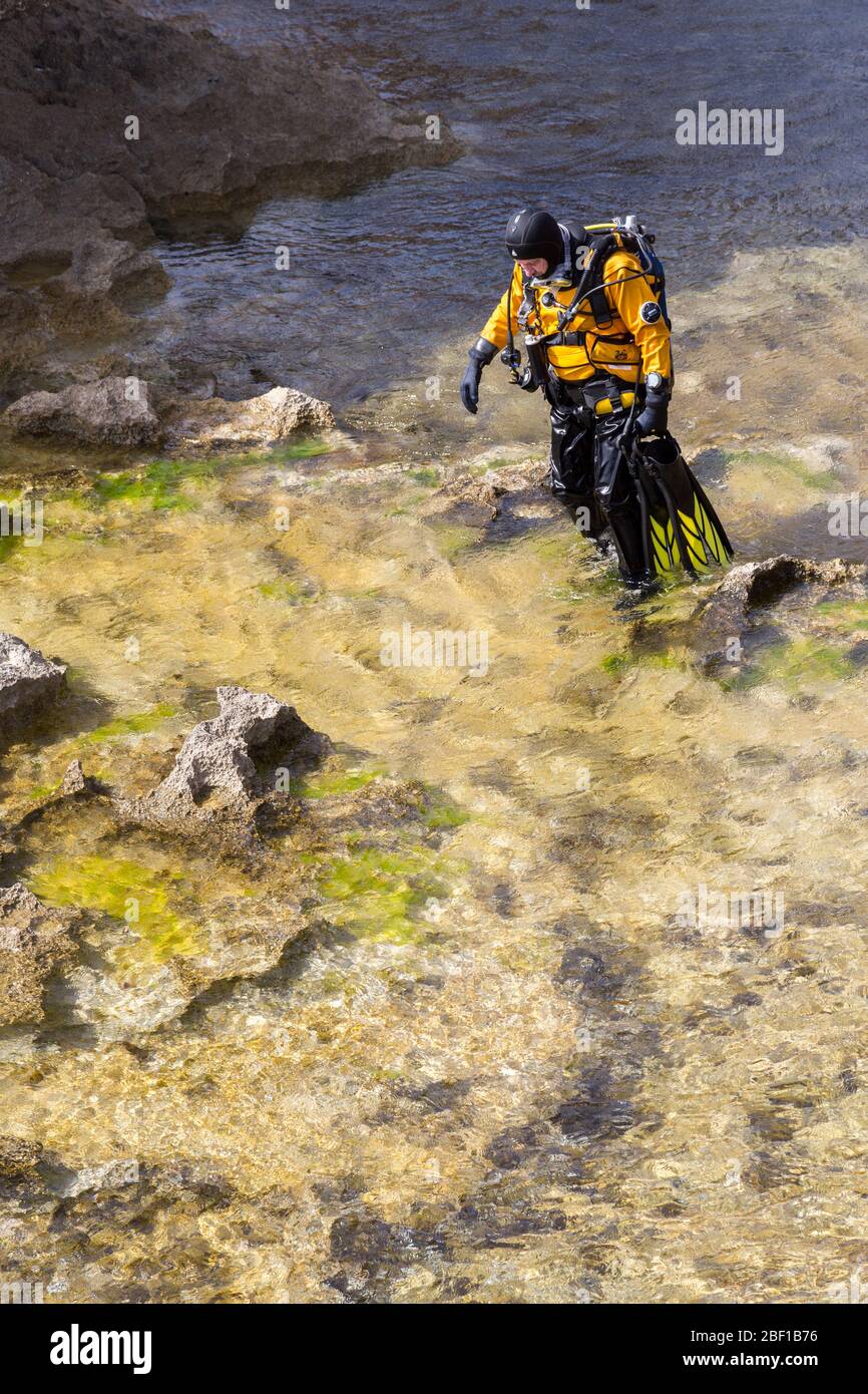 Subaqua diver walking with equipment in the shallows at the Azure Window, Gozo Stock Photo