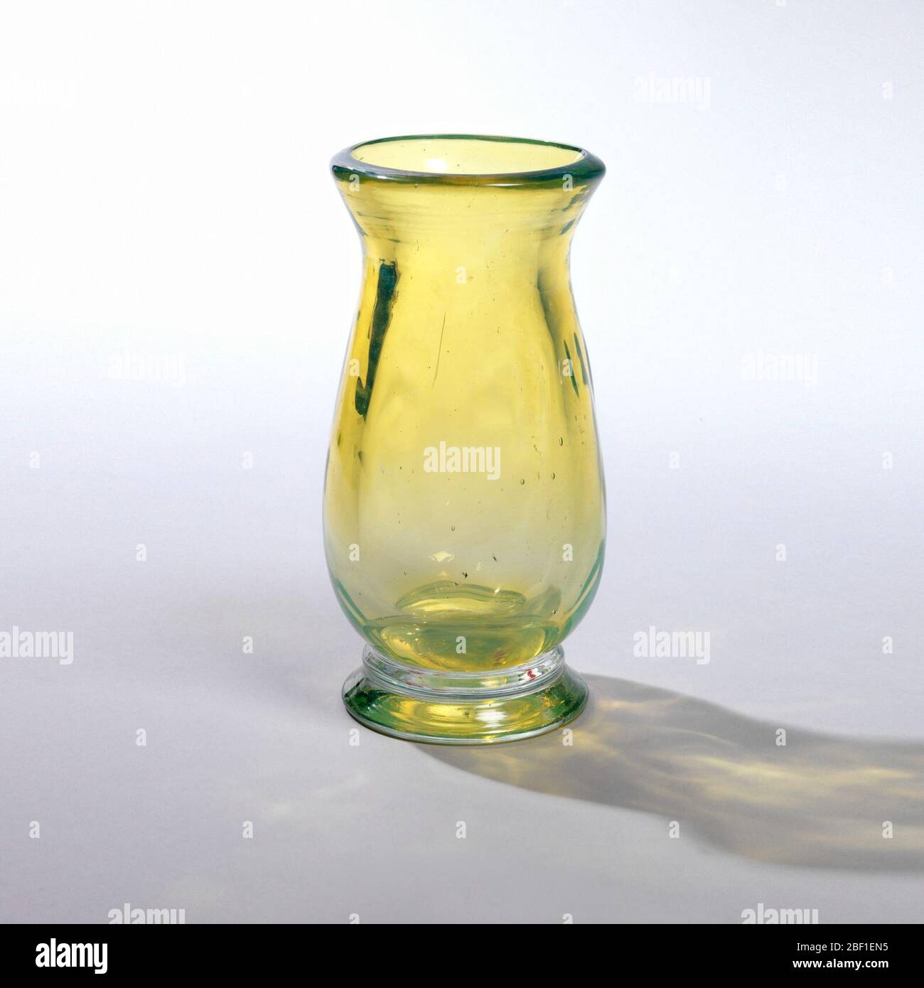 Vase. Elongated ovoid body of thick transparent yellow with milky cast; short wide flaring neck; narrow cushion between body and clear foot. Stock Photo