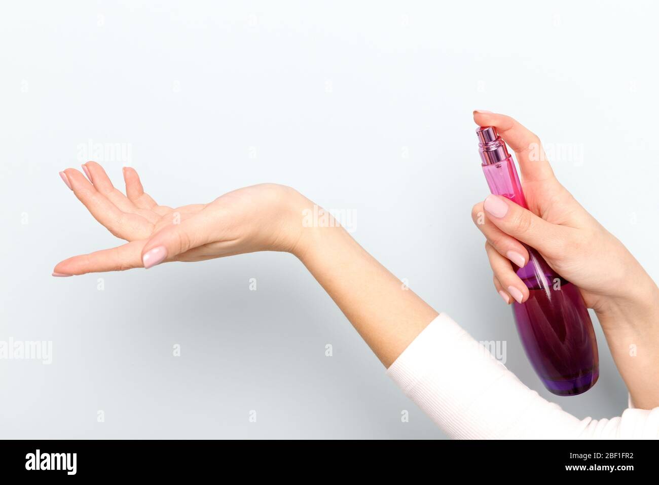 Over Spraying Close up of woman applying/spraying perfume on her wrist over light ...