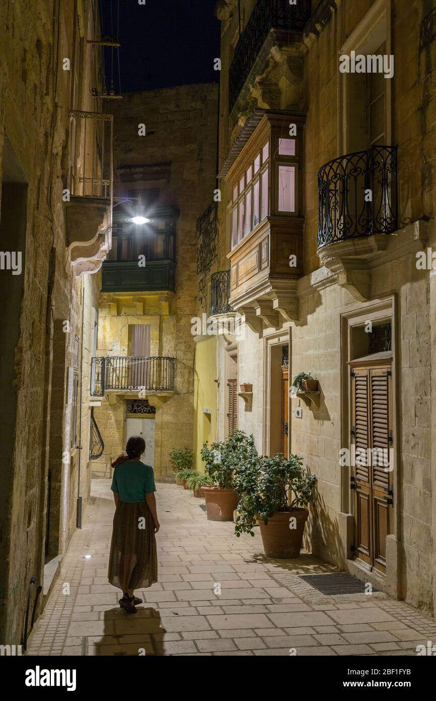 Narrow street with enclosed balcony at night in the fortified city of Birgu aka Vittoriosa, Malta Stock Photo