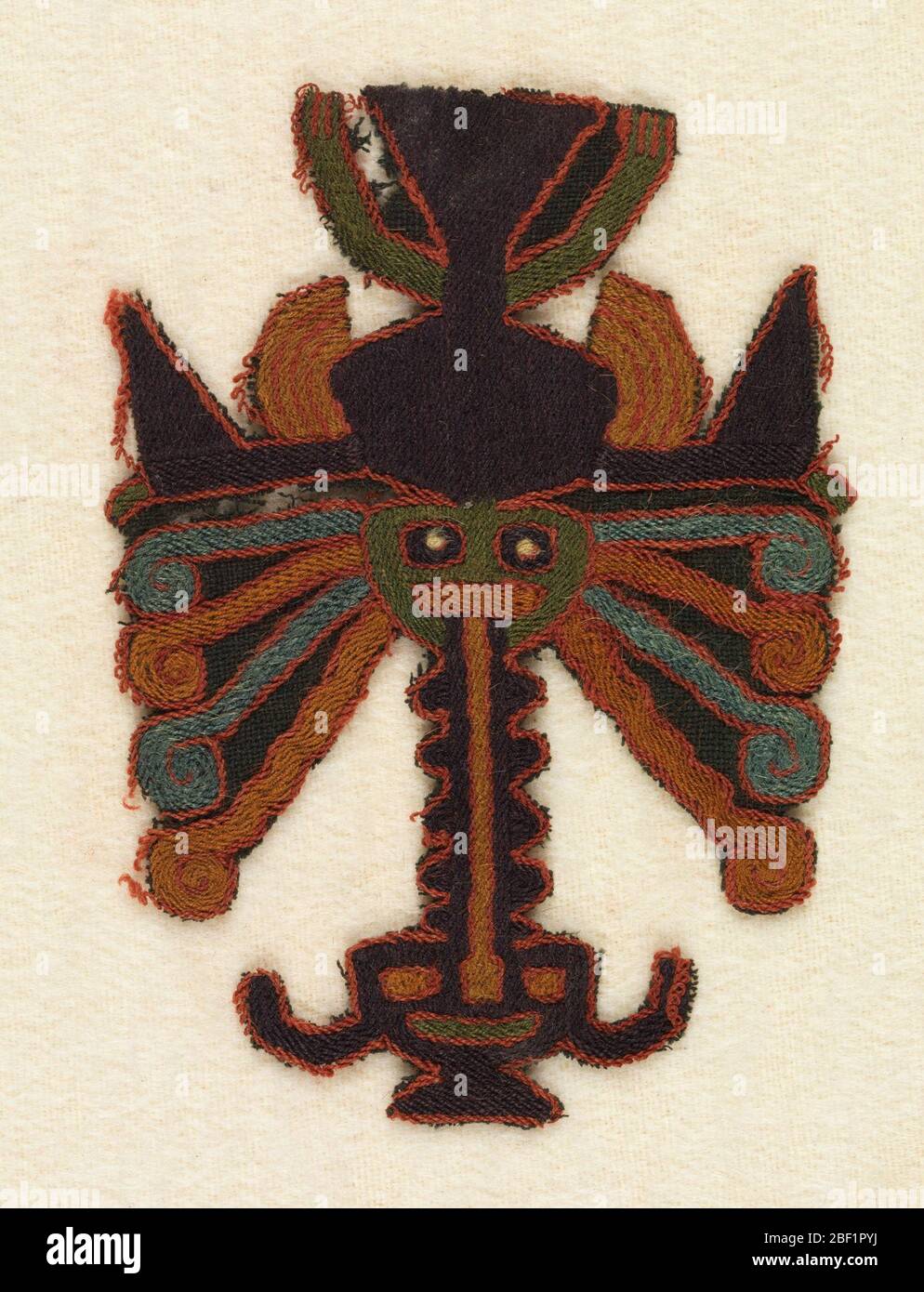 Fragment. Figure wearing a mask with many appendages and trophy head. Embroidered in strong colors. Stock Photo