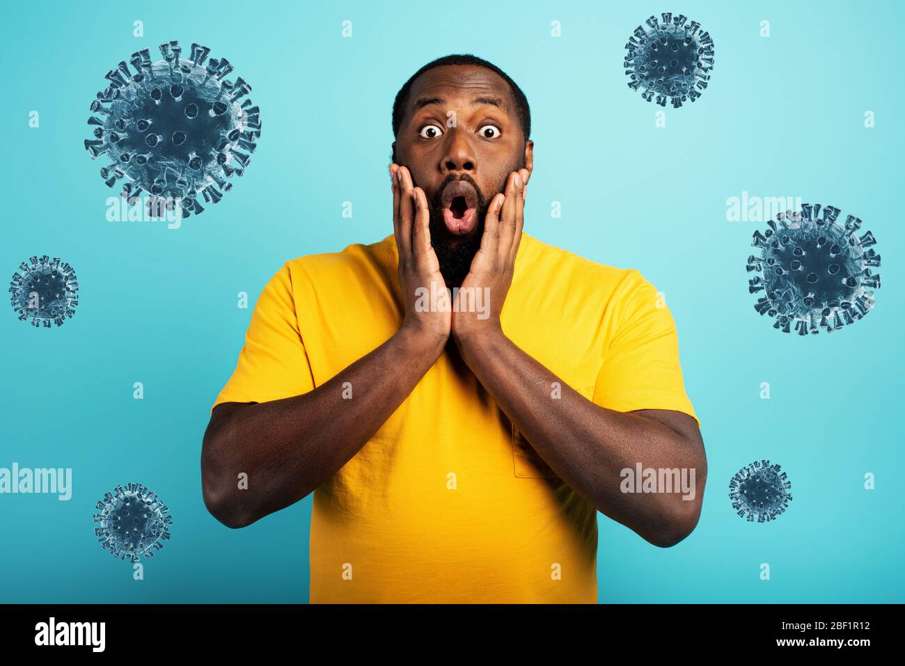 Fearful expression of a boy who is scared to catch the coronavirus. Cyan background. Stock Photo