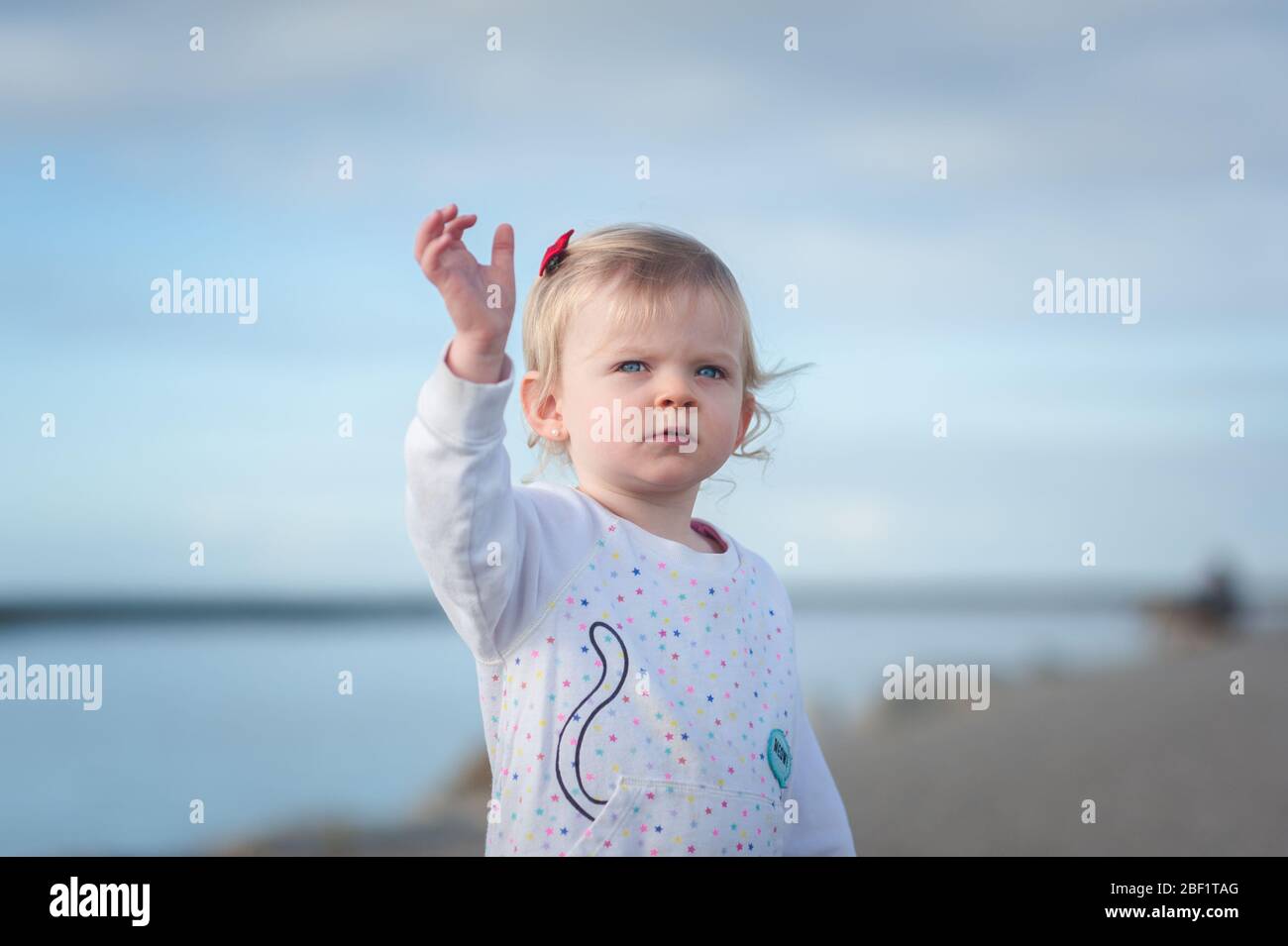 Cute 20 months old toddler girl waving goodbye to the airplanes passing by from the Ballona Creek near the Pacific ocean in Playa Del Rey, CA. Stock Photo