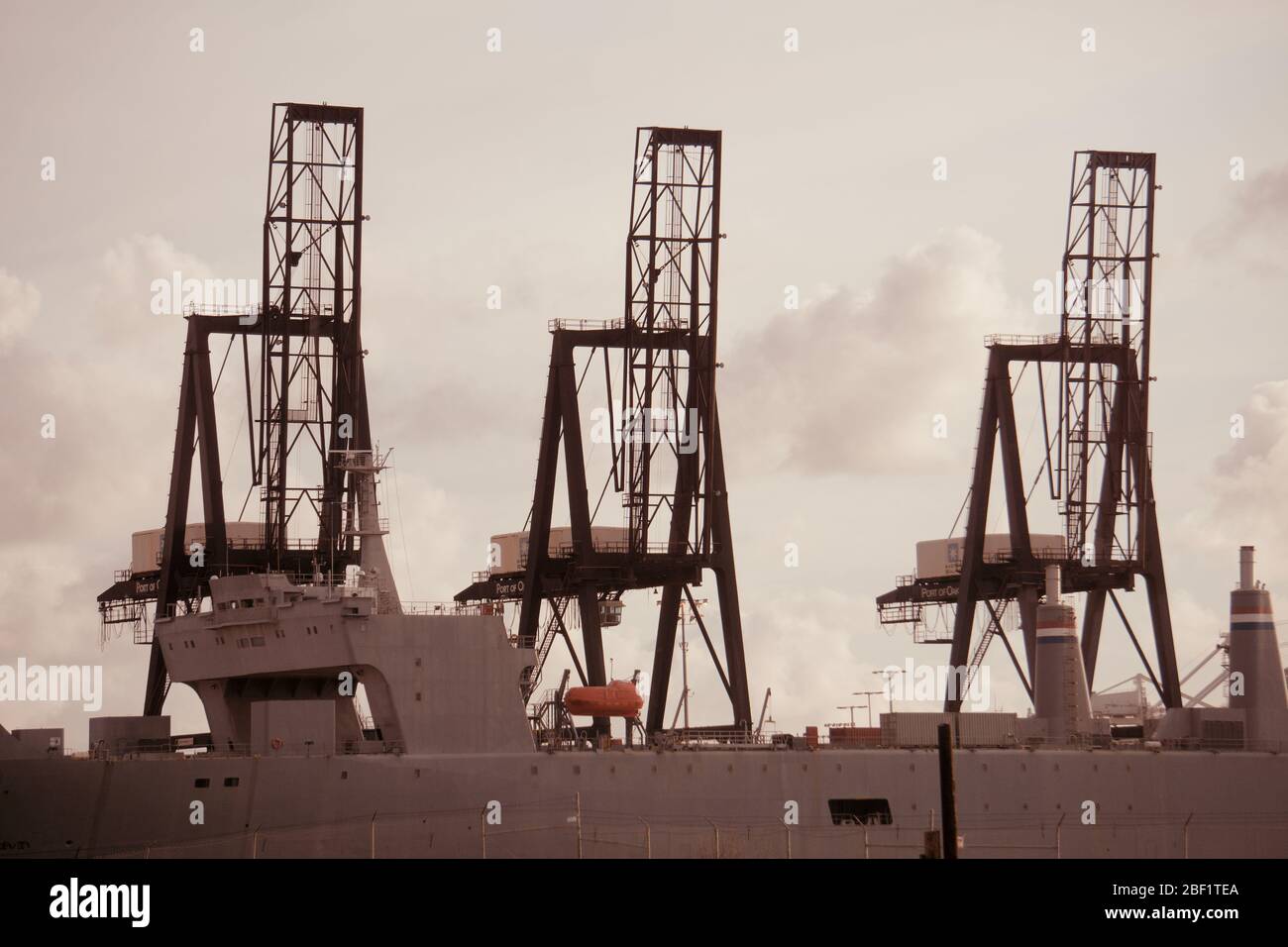 SS Cape Mohican SEABEE barge carrier and war ship at international shipping container terminal with shipping cranes. Outer Harbor, Port of Oakland. Stock Photo