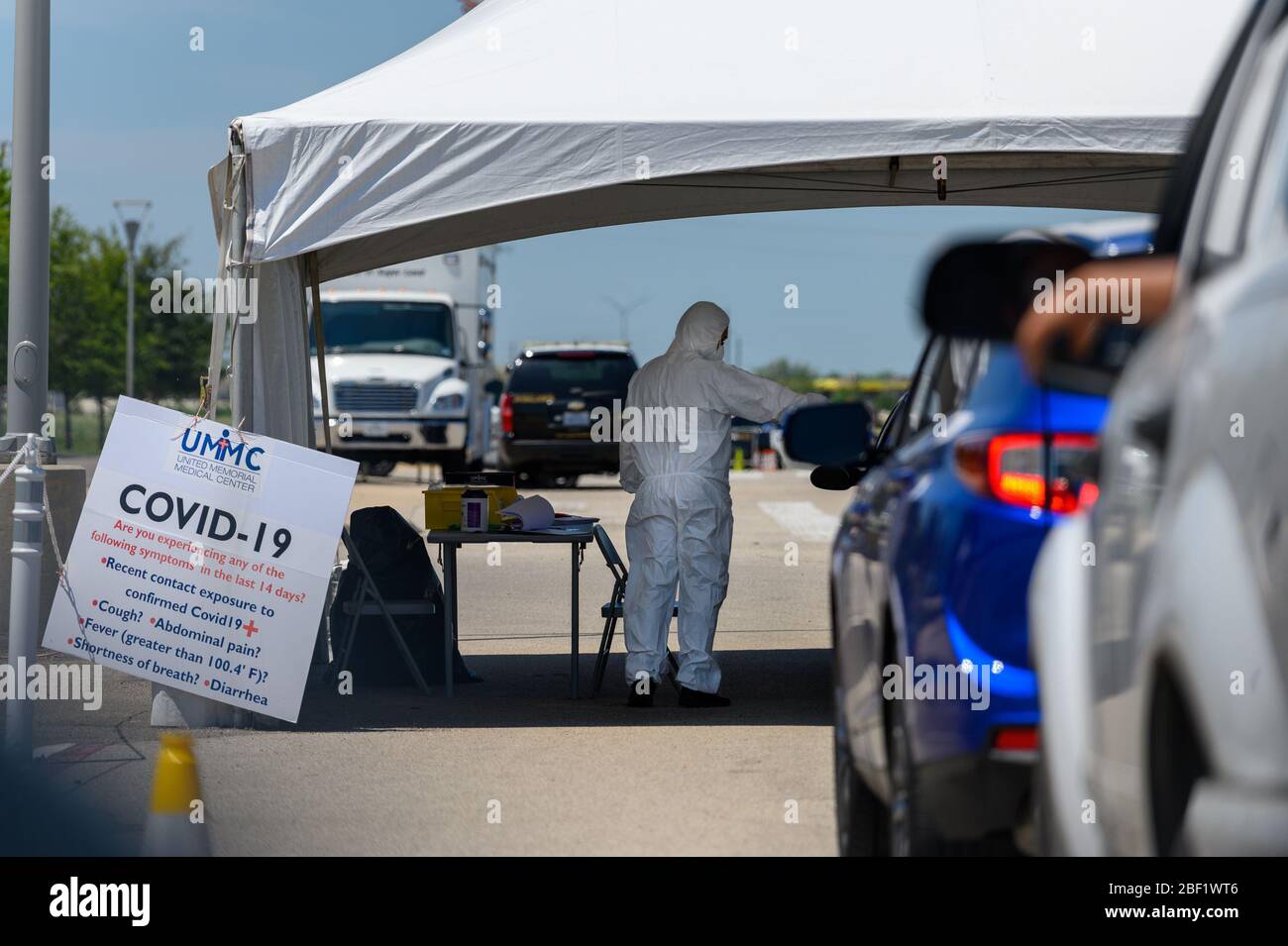 Sugar Land, Texas - April 16, 2020: Dressed in full protective gear a healthcare worker collects information from people sitting inside their car at t Stock Photo