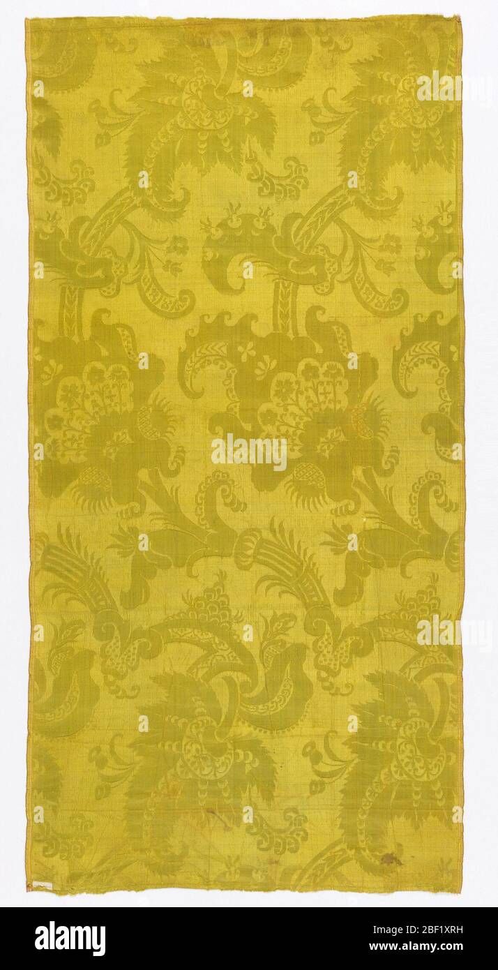 Fragment. Chartreuse damask with a highly conventionalized design of flowers and large scale leaves. Stock Photo