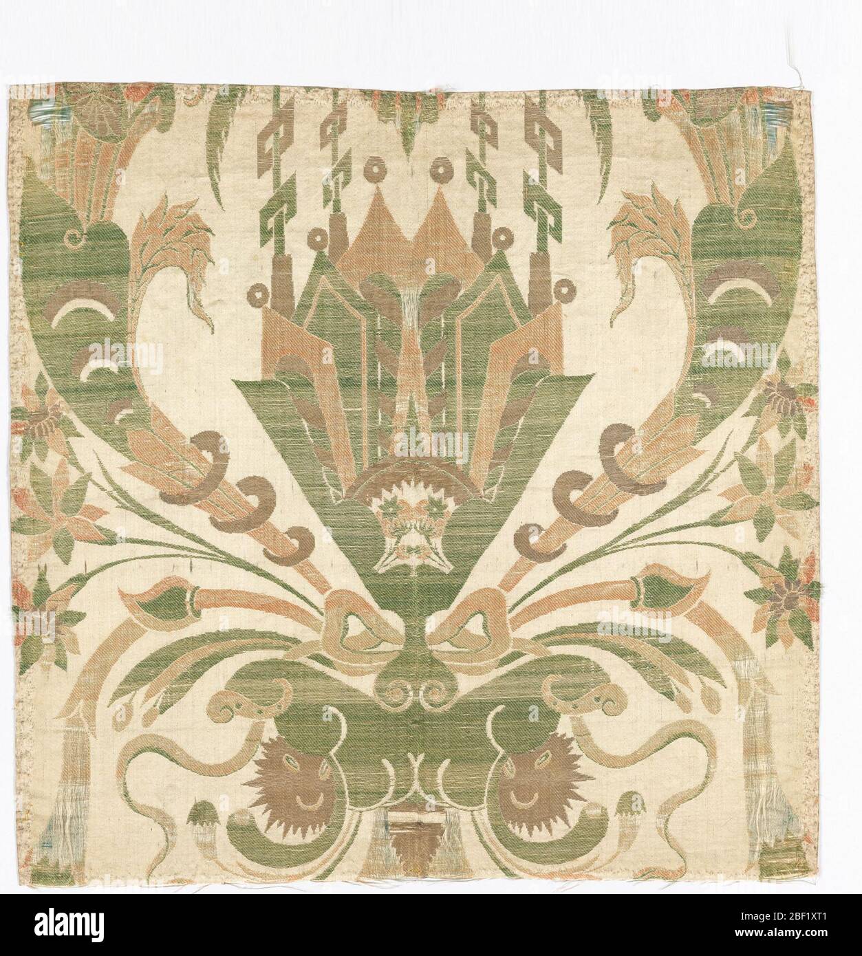 Textile. White satin ground brocaded with symmetrical design in gold, and green, coral and pink silk. Large, central fan-shaped ornamental motif with cornucopia and a bow. Backed with red silk and edged with gold metal lace. Stock Photo