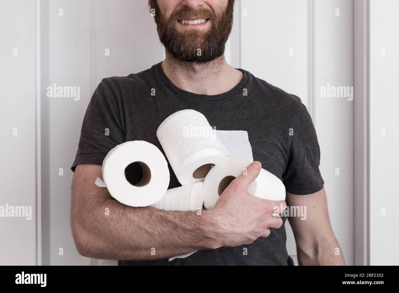 A smiling caucasian man holding rolls of toilet paper the he hoarded. Stock Photo
