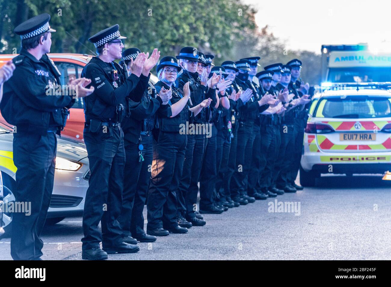 Police officers clapping at Clap for Carers at 8pm outside Southend Hospital in evening to thank NHS and key workers during the COVID-19 Coronavirus Stock Photo
