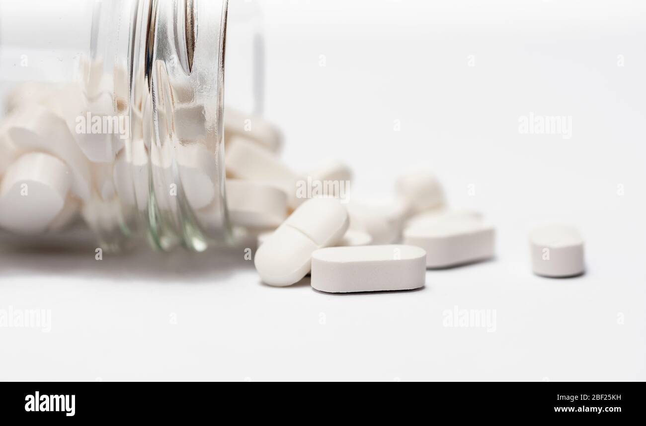 Closeup of a group white pills in crystal bottle on white background close up with copy space. Stock Photo