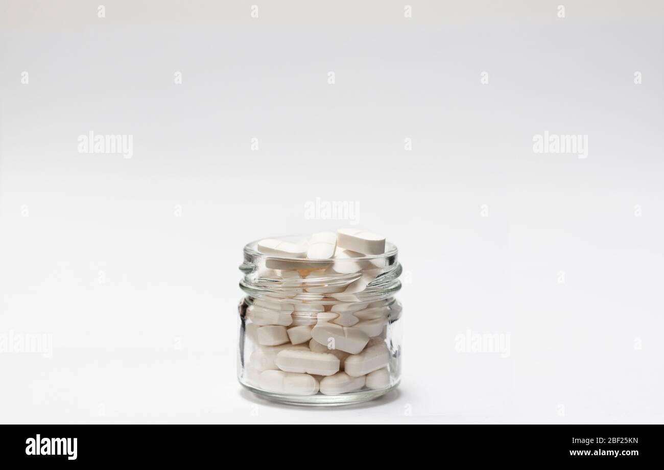 Closeup of a group white pills in crystal bottle on white background close up with copy space. Stock Photo