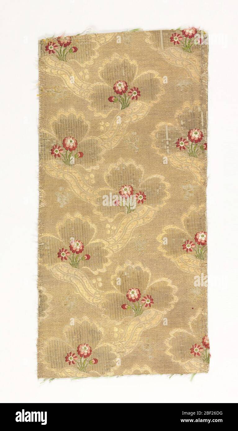 Textile. Cloth of gold brocaded in a small flower pattern of reds and greens. Stock Photo