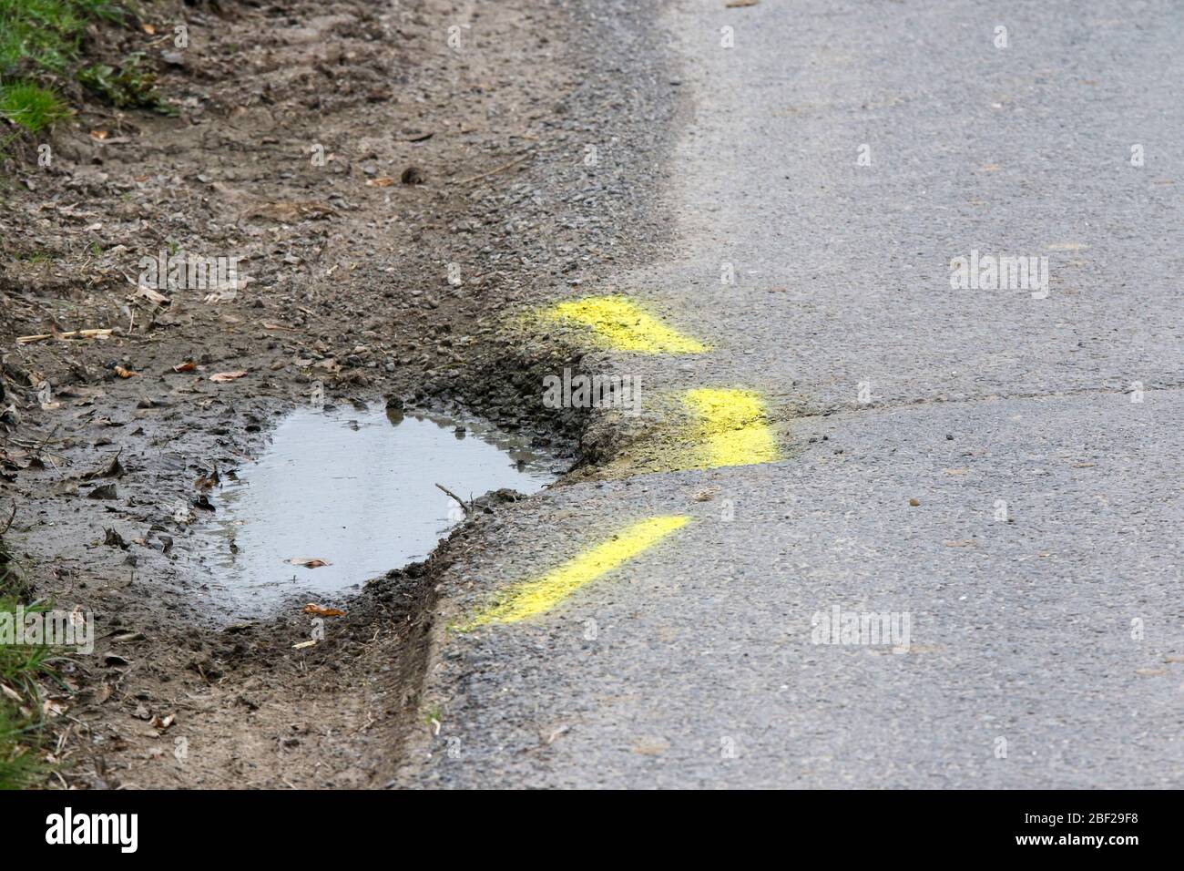 Yellow lines marking a pothole needing repair at the side of a rural country road in Northern Ireland. Stock Photo