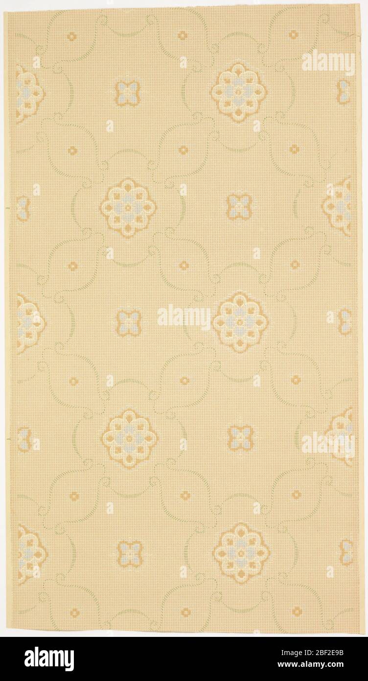 Ceiling paper. Alternating small, medium, and large fleurons in a treillage pattern of scrolls made out of small green lines. Background is covered in a grid of small square dots. Ground is beige. Printed in cream, blue, green, and browns. Stock Photo