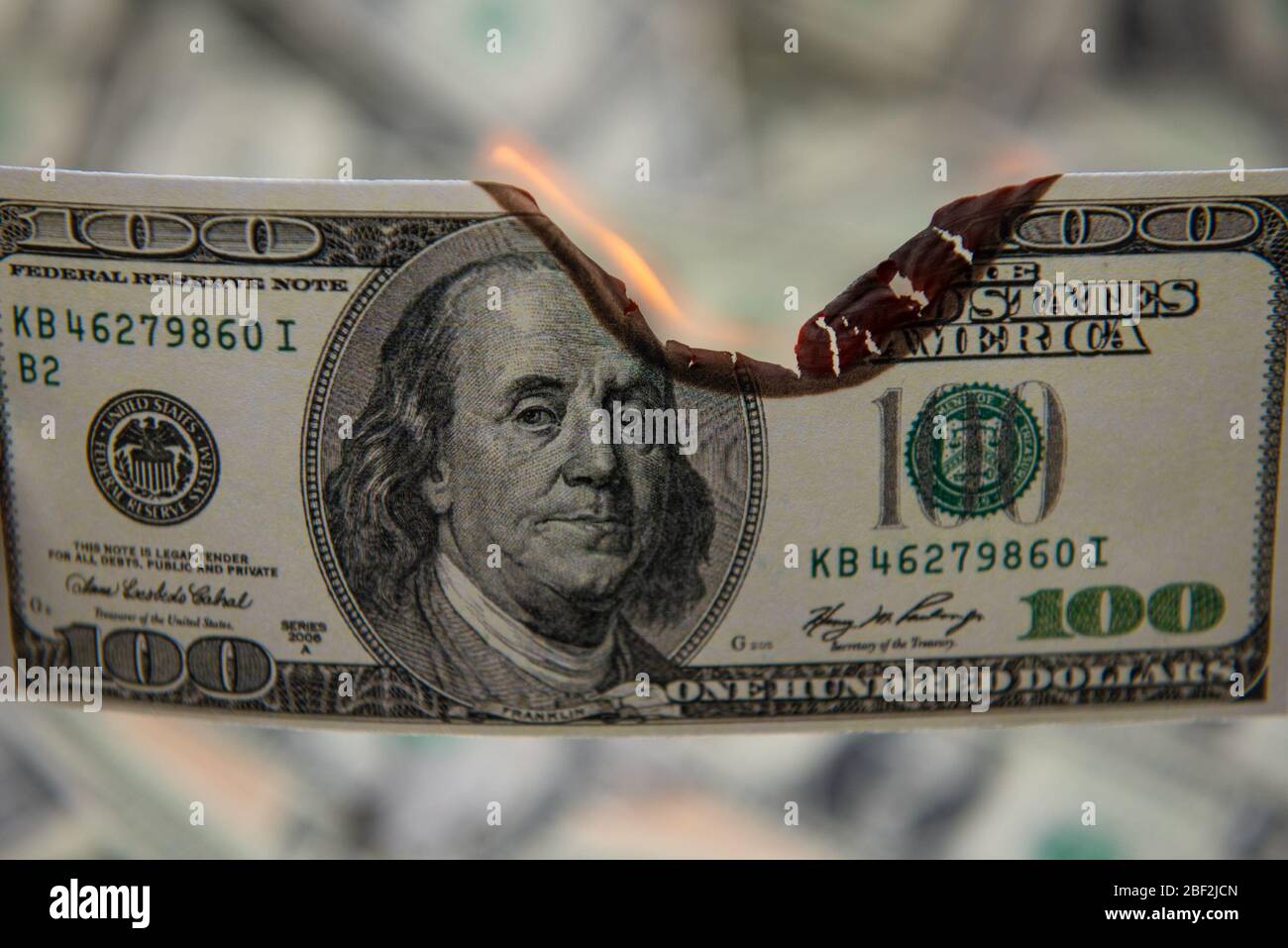 Burning one hundred dollar as symbol economic recession. Stock Photo