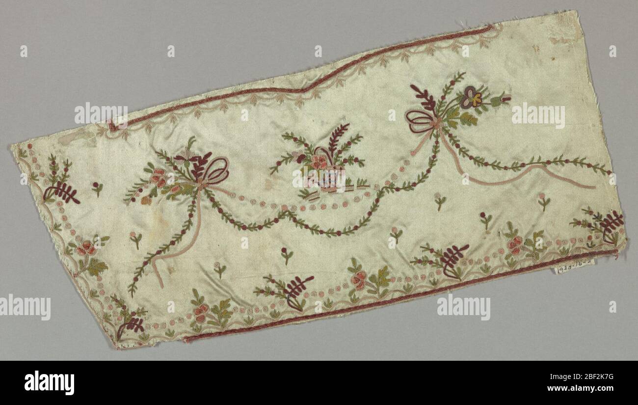 Fragment. Fragment of man's waistcoat in pale green satin embroidered in multicolored silks in a design of flowering vines, floral sprays, baskets of flowers, and ribbons. Stock Photo
