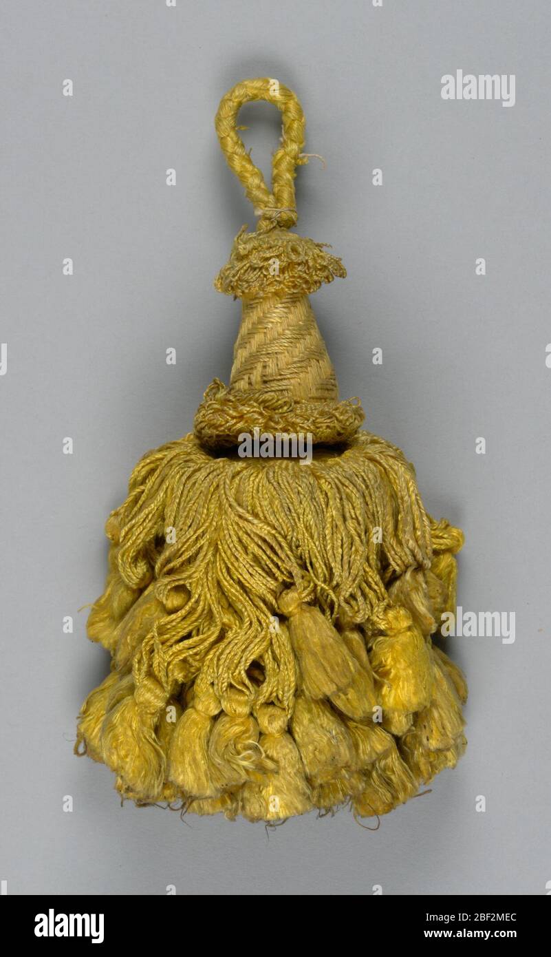 Tassel. Skirt of yellow silk in two lengths, twisted and looped, and each supporting a tassel. Head is cylindrical and swelling toward the base, wrapped with yellow silk threads with collars of looped threads at top and bottom. Loop of yellow silk cord. Stock Photo