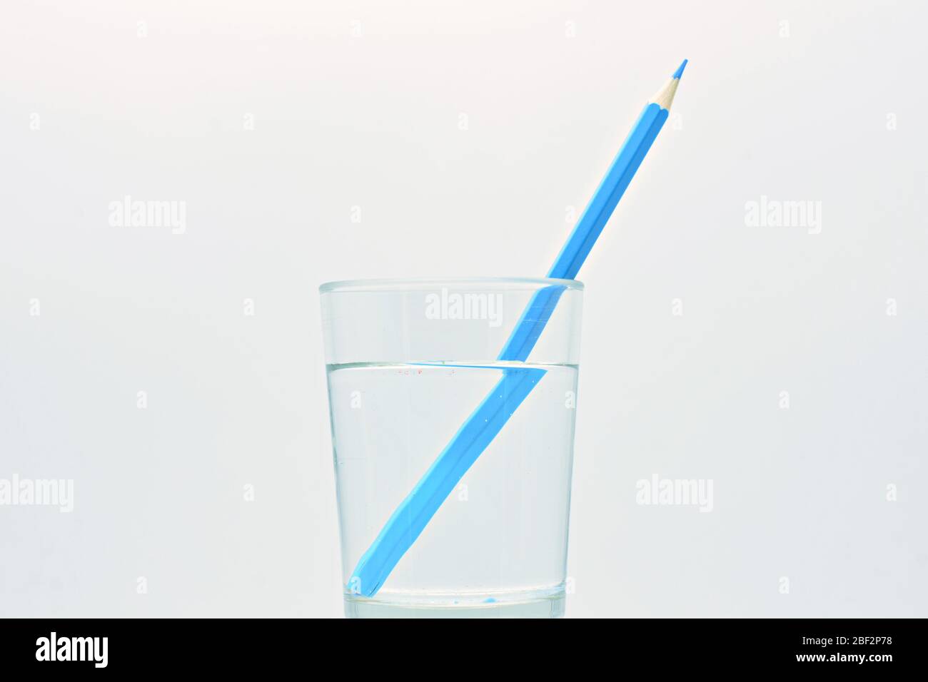Yellow and green pencil, inside a glass filled with water, light refraction explanation Stock Photo