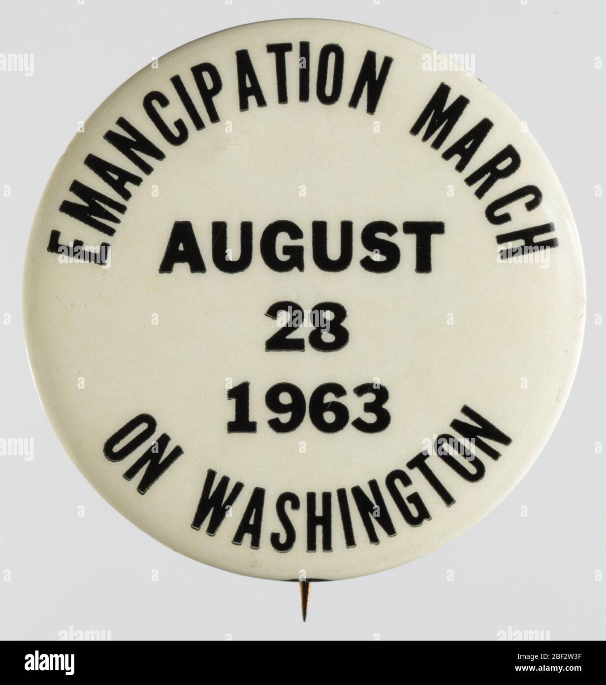 Pinback button for the 1963 March on Washington. A white pin-back button with black text. Around the edges of the front, on the top and bottom, is text surrounding more inner text. Inside the outside circle of text is the date for the March on Washington in 1963. [EMANCIPATION MARCH / AUGUST / 28 / 1963 / ON WASHINGTON]. Stock Photo