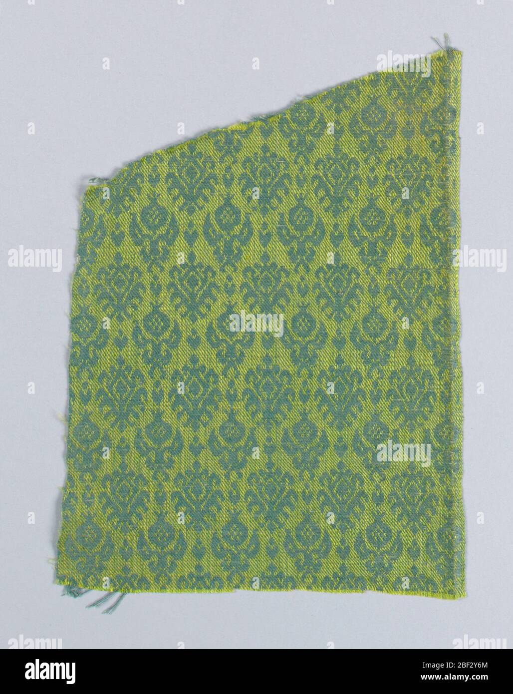 Fragment. Repeat of small symmetrical sprigs with two variations of a pomegranate and leaf motif in alternate rows. One very narrow selvage. Stock Photo