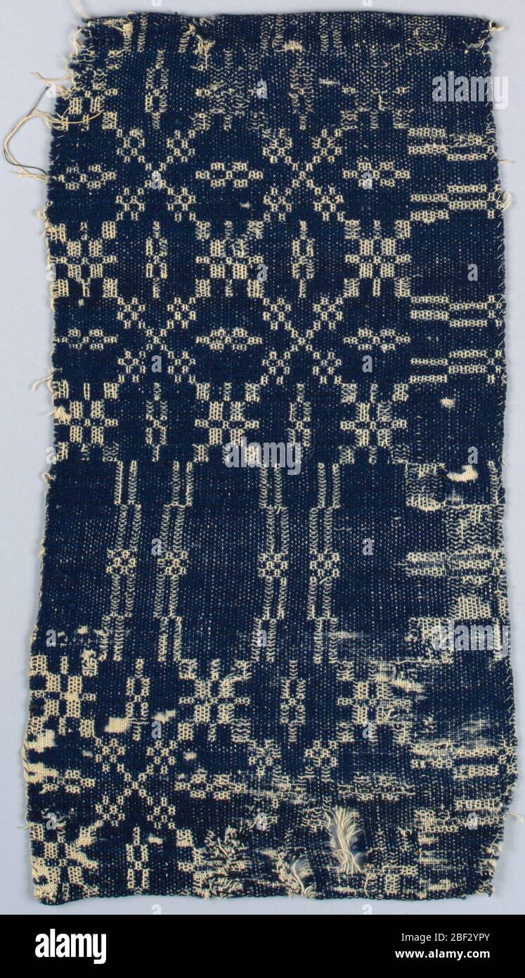 Coverlet fragment. Vertical-horizontal repeat of large squares broken by small geometric trellis framework and other broad bands of geometric patterning. Reversible 'Summer and Winter' weave in dark blue and white. Stock Photo