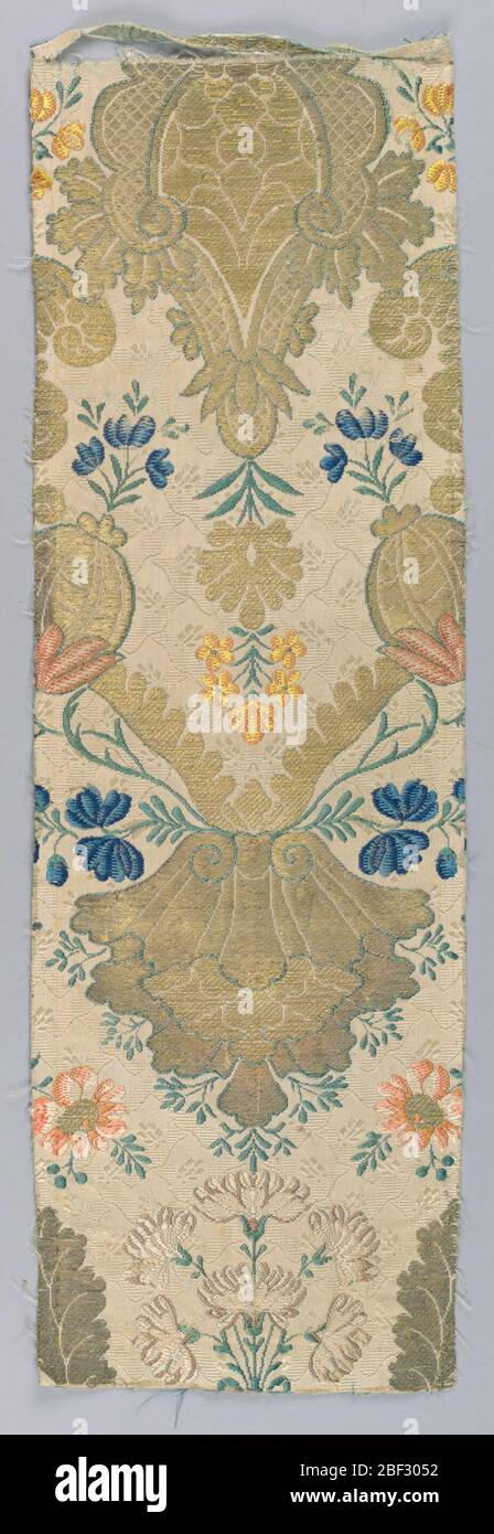 Fragment. Fragment of white silk damask showing floral diaper pattern, with supplementary weft patterning (brocade) in polychrome silk and metallic yarns showing symmetrical design of pomegranates, florals and scrolls. Stock Photo