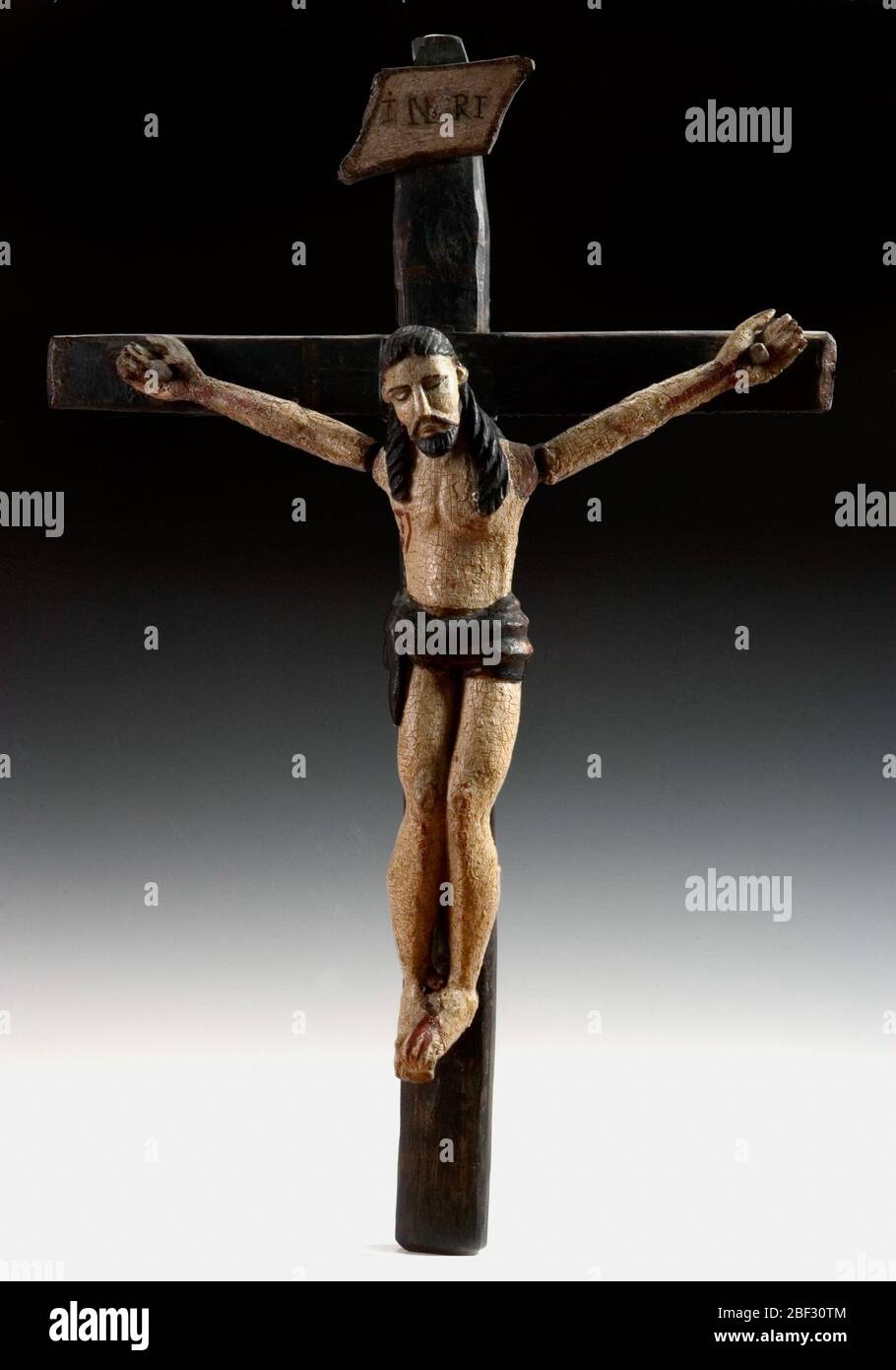Crucifijo. Carvings of the crucified Christ were popular subjects of santeros, artists who created santos, carved wooden images of saints. In this figure, Christ’s limp body looks as if it is shifting, emphasizing the excruciating pain of having his hands and feet nailed to the cross. Stock Photo