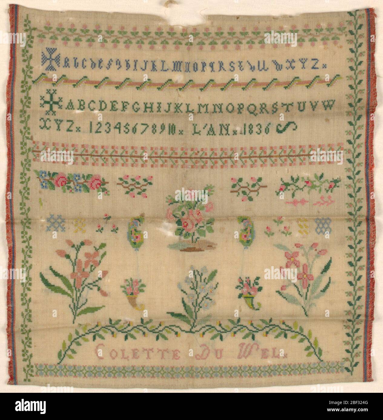 Sampler. Upper third has two alphabets introduced by Maltese crosses and inscription, lower third has isolated floral motifs. Floral borders on four sides. Stock Photo