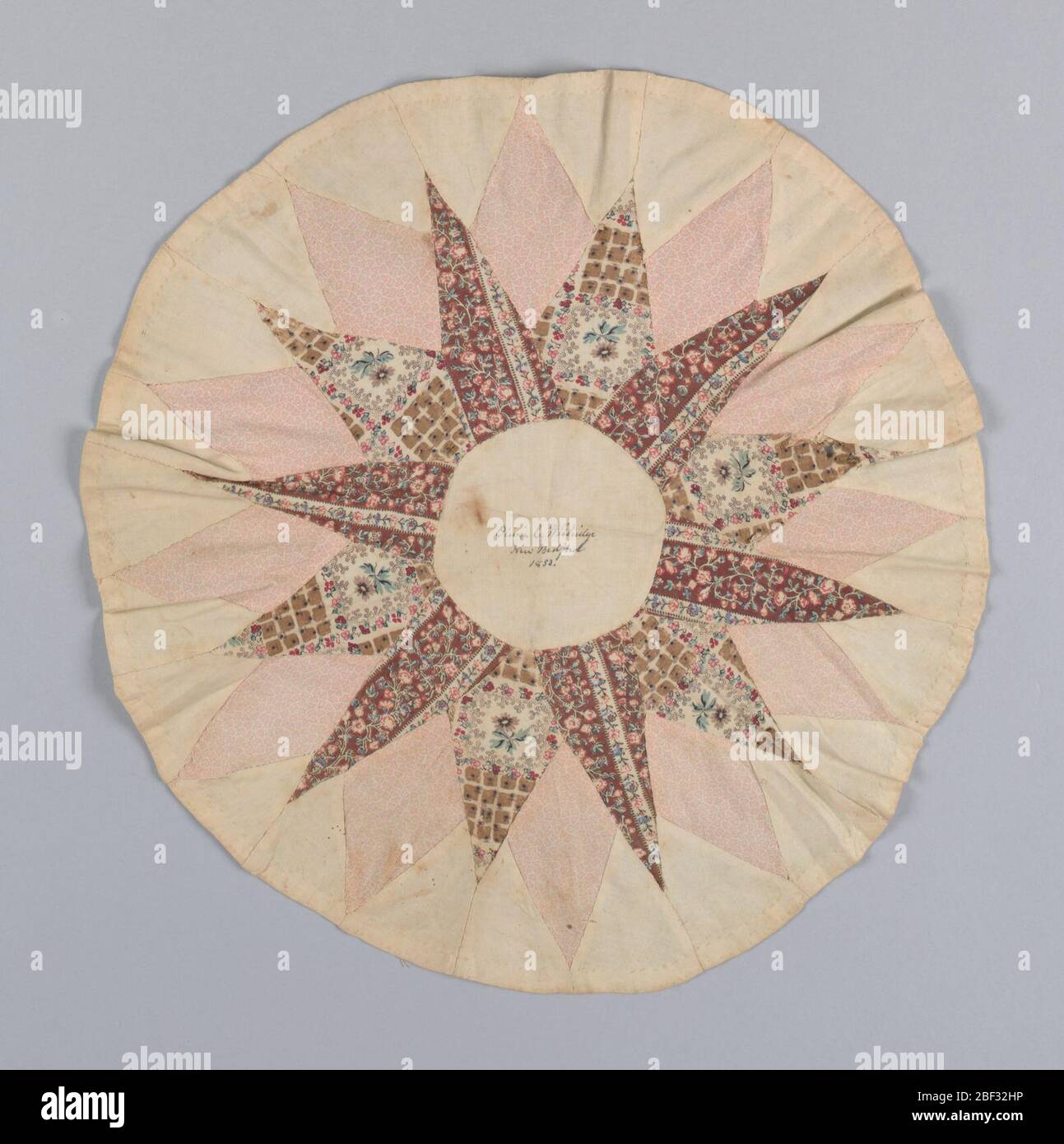 Mariners Compass. Patchwork medallion with a star pattern in unbleached cotton and three roller-printed cottons in browns, tans and pinks. Handwritten in dark brown ink in the center circle; 'Olivia C. Whitridge, New Bedford, 1853' Stock Photo