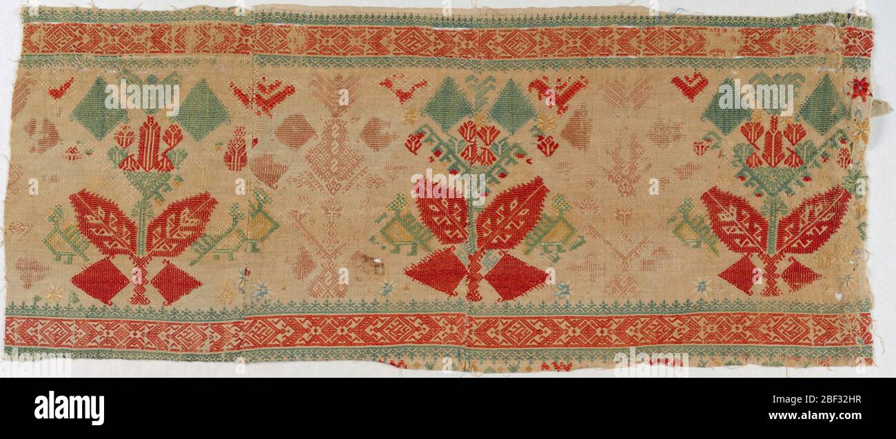 Border. Fragment pieced in two places. Cream-colored hand-woven linen, embroidered in red, green, yellow, blue and pale rose silks. Stylized plant form flanked by birds in profile. Narrow geometric guard borders. Stock Photo
